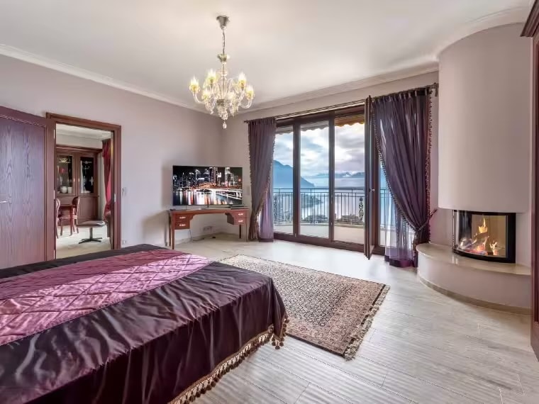 Master bedroom with fireplace and balcony access, lake views
