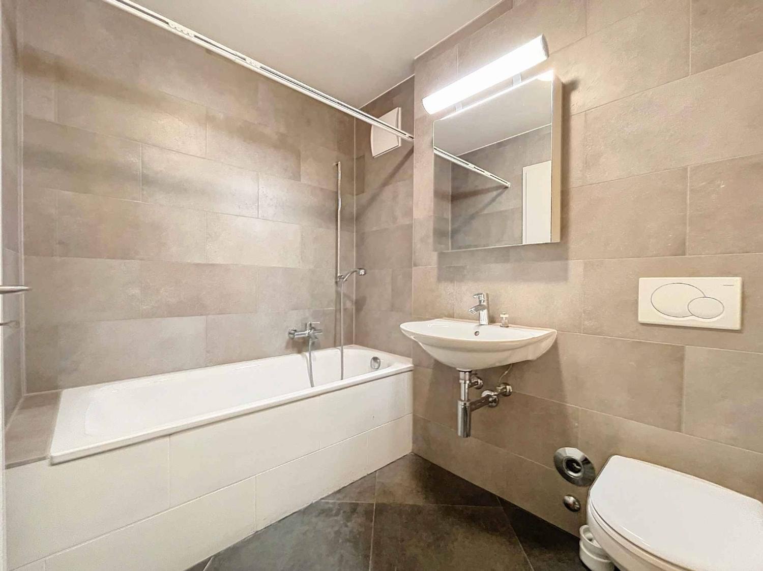 Bathroom with bathtub, beige tiling and WC