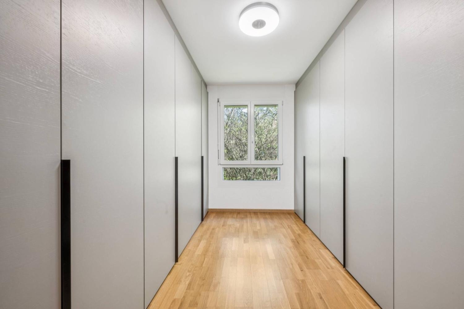 Dressing room with floor-to-ceiling fitted wardrobes and oak parquet flooring